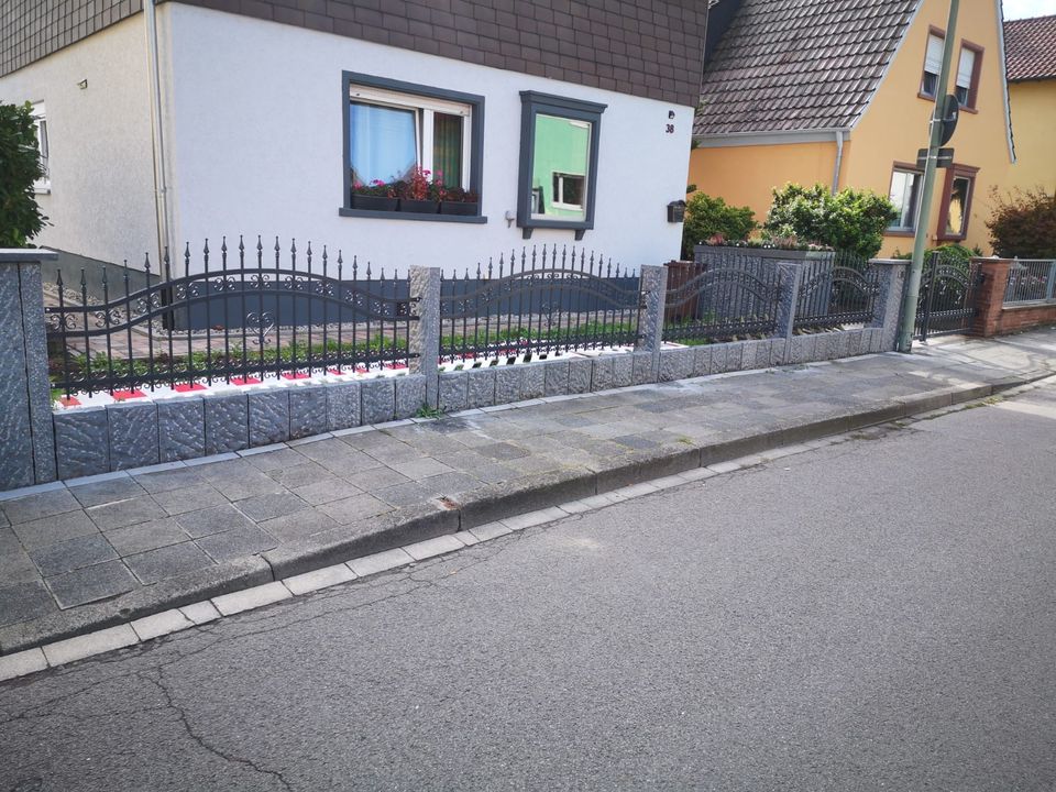 Niedriger Schmuckzaun auf Sockelmauer vor einem Wohnhaus